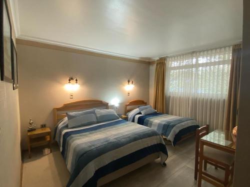 1 dormitorio con 2 camas y ventana en Hotel Libertador Bernardo O´Higgins, en Chillán