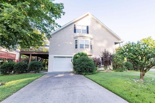 a white house with a garage in a yard at Cozy Pigeon Forge home w hot tub near river in Pigeon Forge