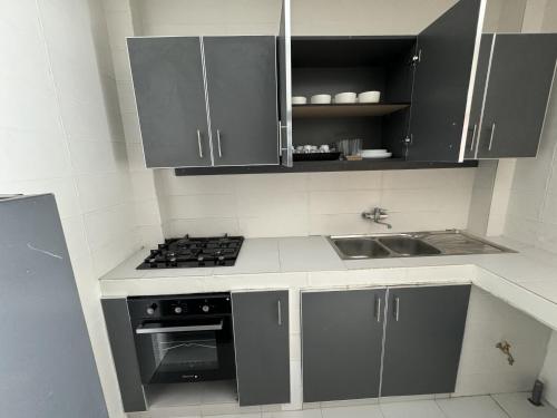 uma cozinha com armários cinzentos, um lavatório e um fogão em Résidences Salsia - Almadies - Studio RDC em Dakar