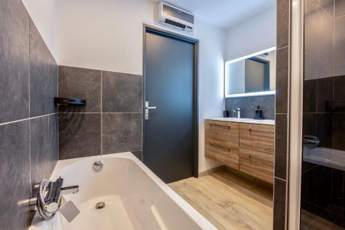 La salle de bains est pourvue d'une baignoire et d'un lavabo. dans l'établissement Maison T4 Climatisée avec Jacuzzi à Lagord, à Lagord