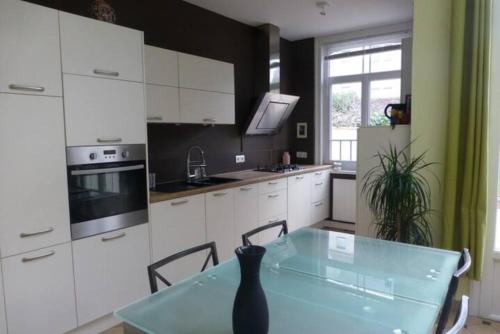 - une cuisine avec des placards blancs et une table avec un vase dans l'établissement Maison confortable et jardin à Lille, à Lille