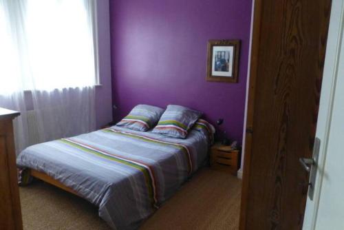 une chambre avec des murs violets et un lit avec des oreillers dans l'établissement Maison confortable et jardin à Lille, à Lille