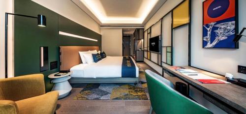 a hotel room with a bed and a desk and chairs at MUSTEL Hotel Guangzhou Nansha in Guangzhou