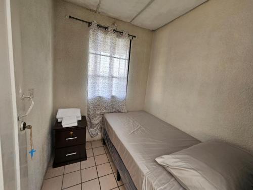 Habitación pequeña con 2 camas y ventana en Buena Vista Home en Nueva San Salvador