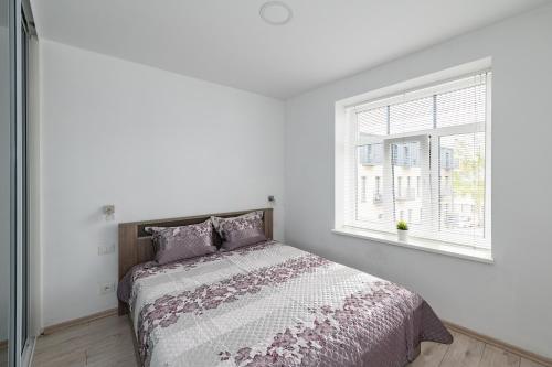 a white bedroom with a bed and a window at Serene Nemunas River View apartment near McDonald by Polo Apartments in Kaunas