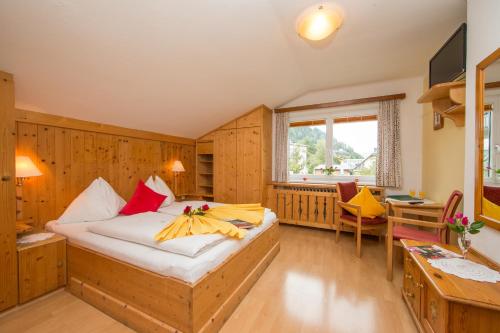a bedroom with a bed and a desk and a window at Hotel Pension Hubertus in Zell am See