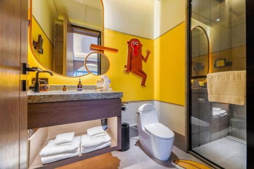 a bathroom with a toilet and a sink and a mirror at MUSTEL Hotel Guangzhou Nansha in Guangzhou