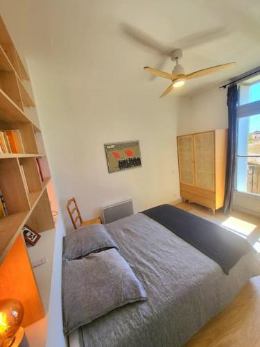 une chambre avec un lit et un ventilateur de plafond dans l'établissement 3 pièces au centre-ville, à Sète
