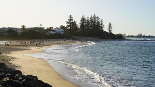 a group of people on a beach with the ocean at Moffat Beach Coastal Contemporary Unit B in Caloundra
