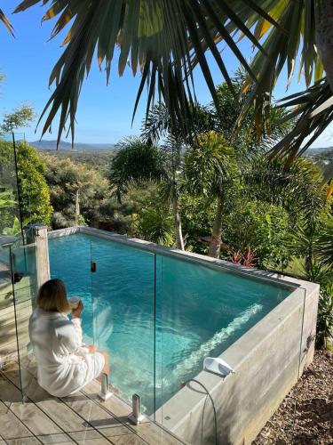 a woman sitting next to a swimming pool at The Opal at Coolum - Mountain and Ocean Views in Yaroomba