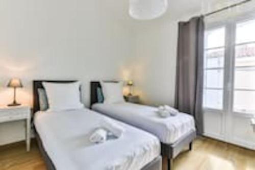 2 Betten in einem Zimmer mit Fenster in der Unterkunft Maison au pied de la plage in Les Sables-dʼOlonne