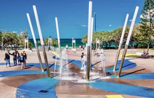 a fountain in a park with people standing around it at Spacious Apartment, Walk To Kings Beach in Caloundra