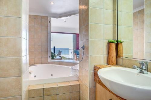 ein Badezimmer mit einer Badewanne, einem Waschbecken und einem Spiegel in der Unterkunft Top Floor Unit With Private Rooftop Terrace in Caloundra