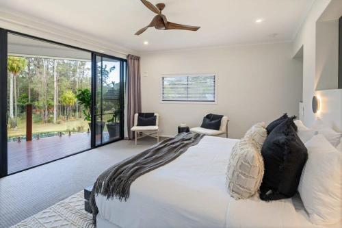 a bedroom with a large bed with a ceiling fan at The Noosa Ranch- Where Nature meets Luxury in Tinbeerwah