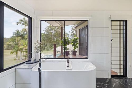 a bathroom with a white tub and a large window at The Noosa Ranch- Where Nature meets Luxury in Tinbeerwah