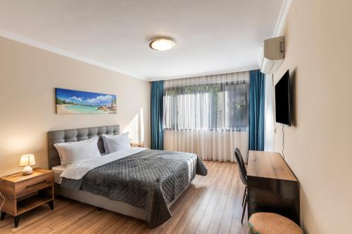 a bedroom with a bed and a desk and a television at Bissera premium apartments in Sofia