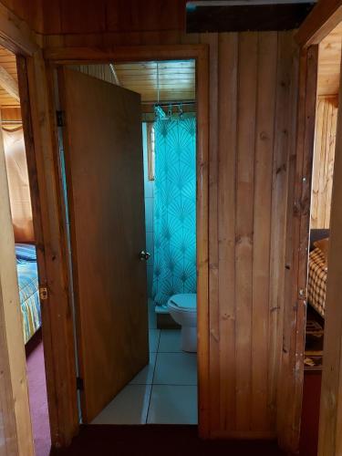 a bathroom with a toilet and a door to a room at Cabañas frente al mar 