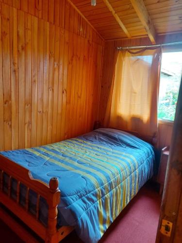 a small bed in a wooden room with a window at Cabañas frente al mar 