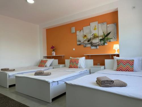 3 camas en una habitación con pared de color naranja en Flamingo Resort, en Belgrado