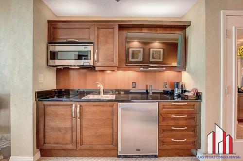 a kitchen with wooden cabinets and stainless steel appliances at MGM Signature-21-609 Strip View Jacuzzi Studio in Las Vegas