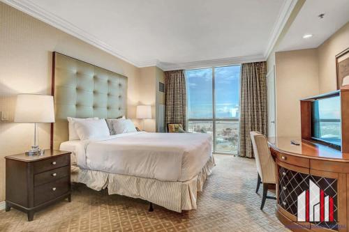 een slaapkamer met een bed, een bureau en een televisie bij MGM Signature-10-714 1Br Balcony Suite Accessible in Las Vegas