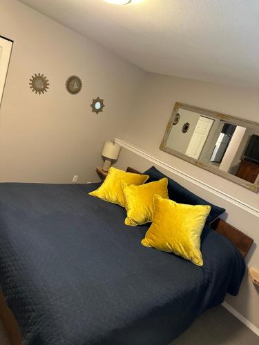 um quarto com uma cama azul e almofadas amarelas em Pleasant Valley Vacation Suite em Nanaimo