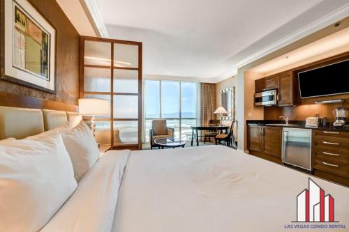 a bedroom with a large white bed and a kitchen at MGM Signature-16-704 Jacuzzi Studio in Las Vegas