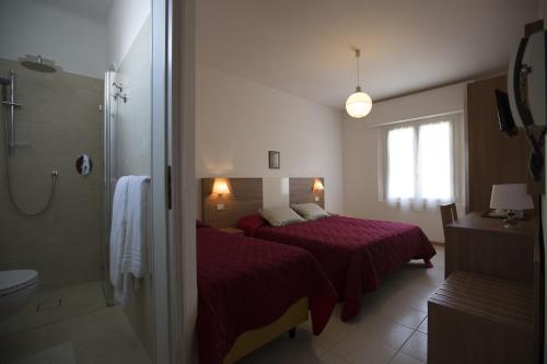 a hotel room with two beds and a shower at Hotel Brunella in Rimini