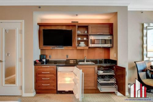 uma cozinha com armários de madeira e uma televisão de ecrã plano em MGM Signature-10-717 Strip View Balcony Studio em Las Vegas