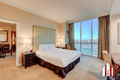 a bedroom with a bed and a desk and a large window at MGM Signature-29-602 1Br 2Ba Balcony Jacuzzi Suite in Las Vegas