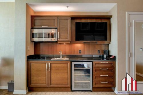 a kitchen with wooden cabinets and a sink and a microwave at MGM Signature-08-604 Jacuzzi Studio in Las Vegas