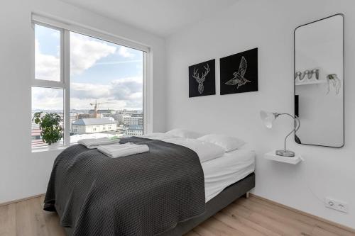 a white bedroom with a bed and a large window at Spacious Luxury 3BR Apartment with 2 bathrooms 1003 in Reykjavík