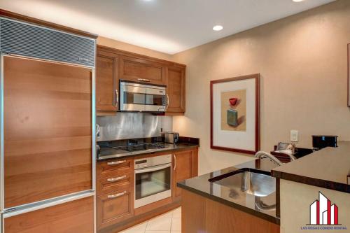 a kitchen with wooden cabinets and a stainless steel refrigerator at MGM Signature-20-608 1Br 2Ba Balcony Jacuzzi Suite in Las Vegas