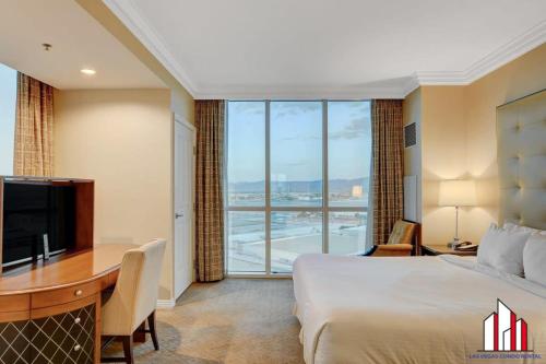ein Hotelzimmer mit einem Bett, einem Schreibtisch und einem großen Fenster in der Unterkunft MGM Signature-20-620 1Br 2Ba Balcony Suite in Las Vegas