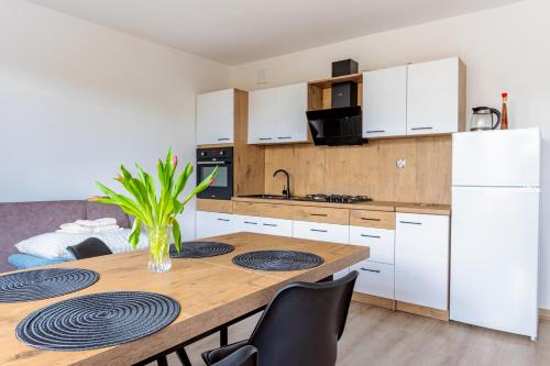 a kitchen with a wooden table and white cabinets at Pokoje i Apartamenty Marek - Niedaleko Plaży in Ostrowo