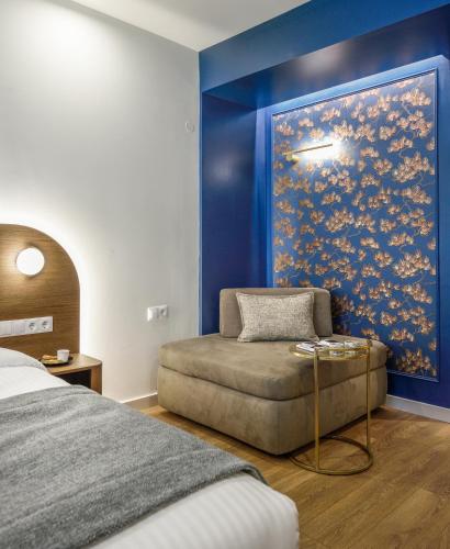 a bedroom with a bed and a chair and a painting at Epineio Comfort Living in Litochoro