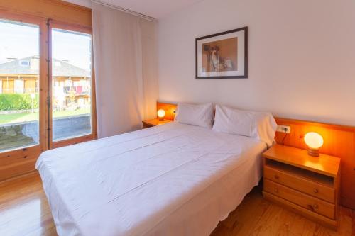 1 dormitorio con cama blanca y ventana grande en Duplex Nord en Alp