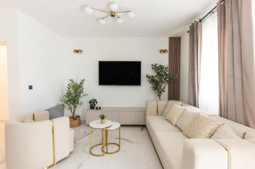 a white living room with two white couches and a tv at Villa Koludrovac in Kaštela