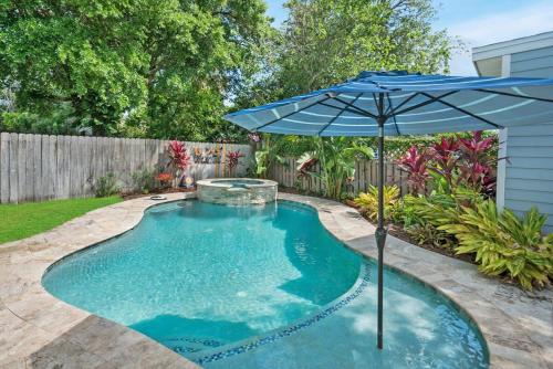 a swimming pool with an umbrella and a fountain at Charming Cottage w Pool, Walkable to Downtown in St. Augustine