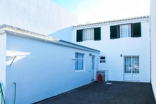 a white building with a parking lot in front of it at Vieira Rooms Natural Pools in Ponta Delgada