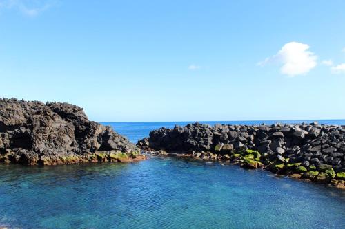 un gran cuerpo de agua junto a algunas rocas en Vieira Rooms Natural Pools, en Ponta Delgada