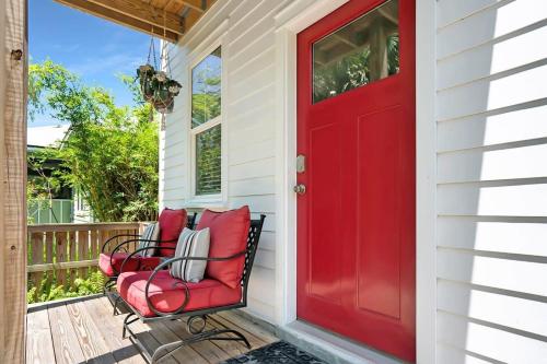 a red door on a porch with two chairs at Downtown Home with Hot Tub, BBQ, Near Ice Plant! in Saint Augustine