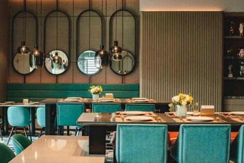 a dining room with tables and chairs and mirrors at MUSTEL Hotel Guangzhou Nansha in Guangzhou