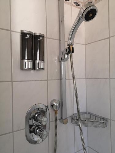 a shower head in a white tiled bathroom at Das Ferienhaus in Papenburg