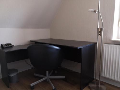 a black desk with a chair and a lamp at Das Ferienhaus in Papenburg