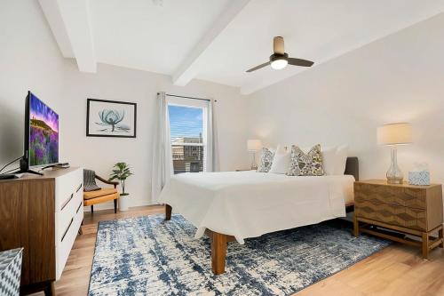 a white bedroom with a bed and a tv at Park It At the Butterfield Garage, Historic Pre-Prohibition Style Apt in the Heart of Downtown in Saint Augustine