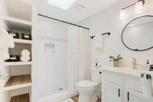a white bathroom with a toilet and a mirror at Park It At the Butterfield Garage, Historic Pre-Prohibition Style Apt in the Heart of Downtown in Saint Augustine