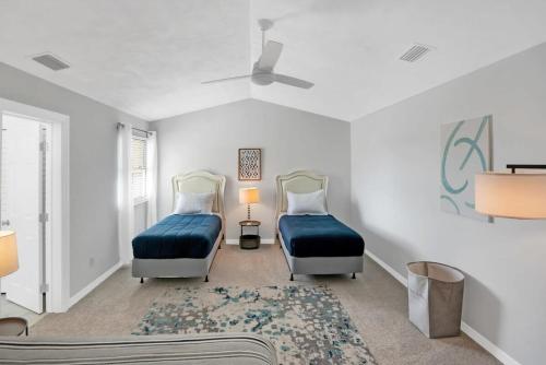 sypialnia z 2 łóżkami i wentylatorem sufitowym w obiekcie Sapphire Skies! Sweet Beach Condo Steps from the Sand and Surf w mieście St. Augustine