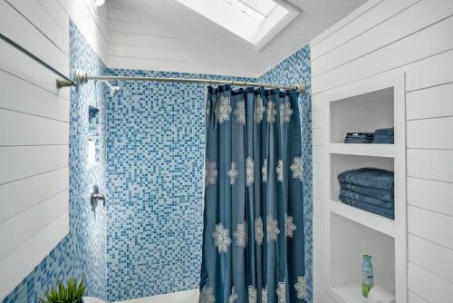 a bathroom with a shower with a blue tiled wall at Sapphire Skies! Sweet Beach Condo Steps from the Sand and Surf in Saint Augustine