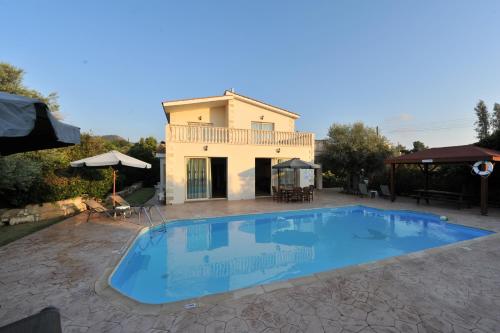 a villa with a swimming pool in front of a house at Jaime Villa Cyprus in Argaka